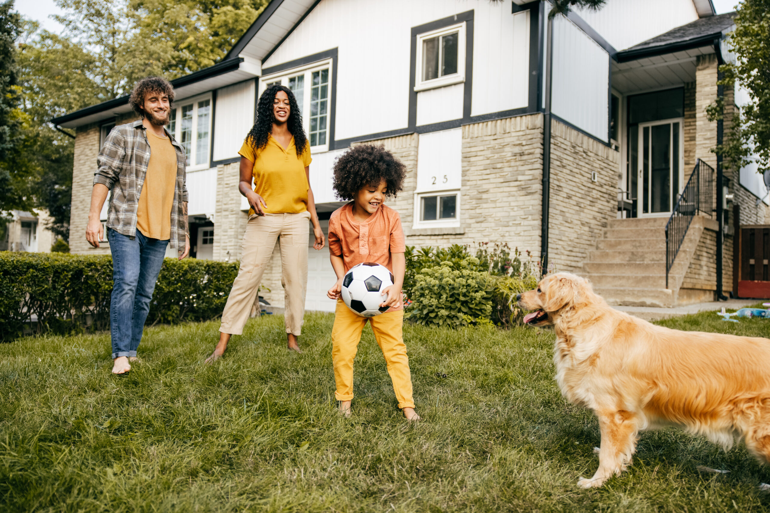 Shot of family playing soccer together with their dog.